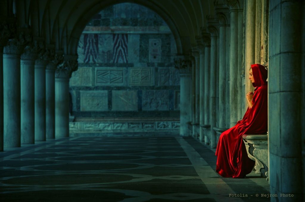 Woman in red cloak praying alone